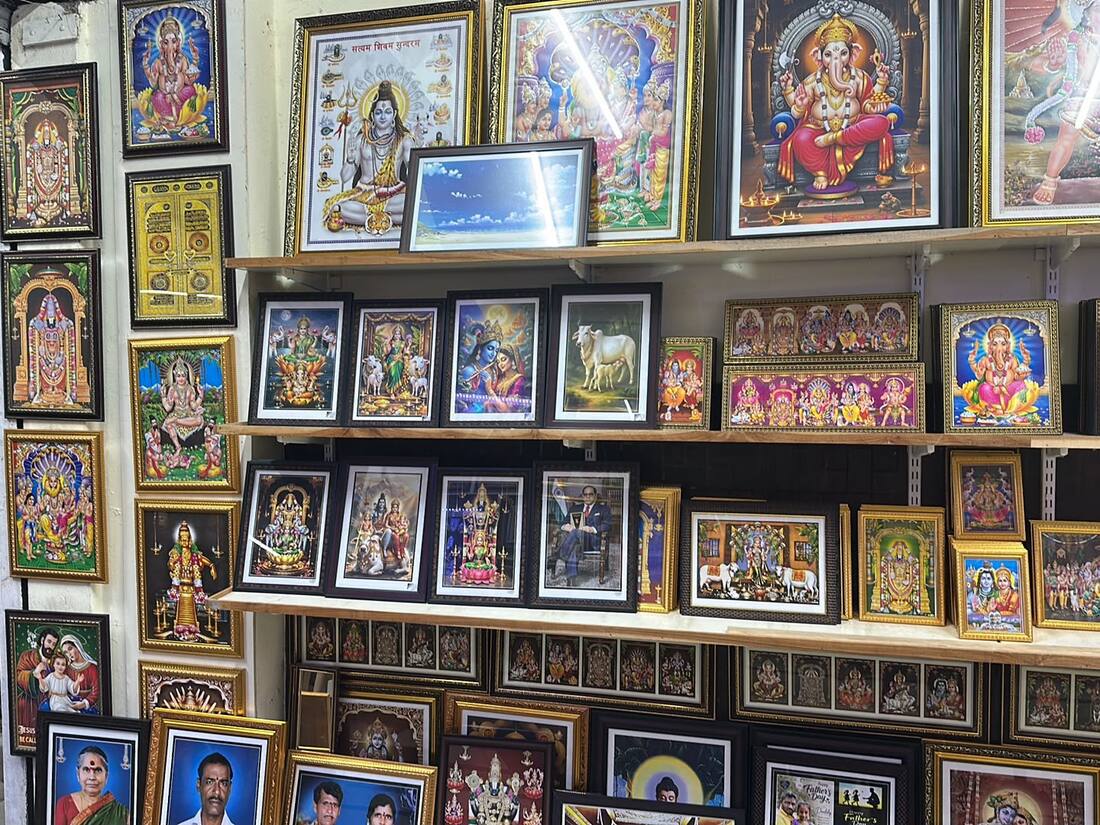 Shelves of framed devotional prints and personal portraits inside Frame Crafts